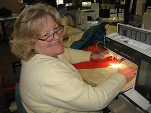 Lynn is sewing her applique to the background at Quilting Adventures